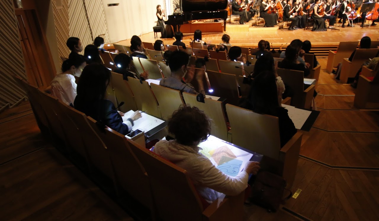 会場全体を包む光の演出とオーケストラ